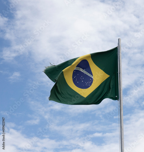 Brazil. Brazilian flag hoisted. Blue sky with clouds, strong wind. Order and progress, legibly in the center. Fabric a little worn due to age.