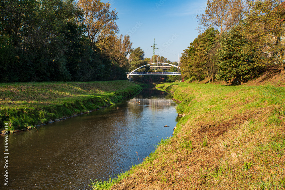 River with bridge over and tress around during autumn day with clear sky