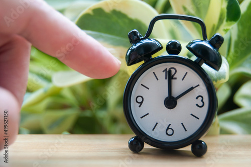 Hand pointing alarm clock that points at 2 pm. Copy space concept photo