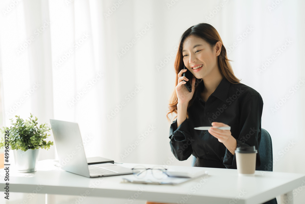 Asian businesswoman in formal suit in office happy and cheerful during using smartphone and working Asian businesswoman in formal suit in office happy and cheerful during using smartphone and working