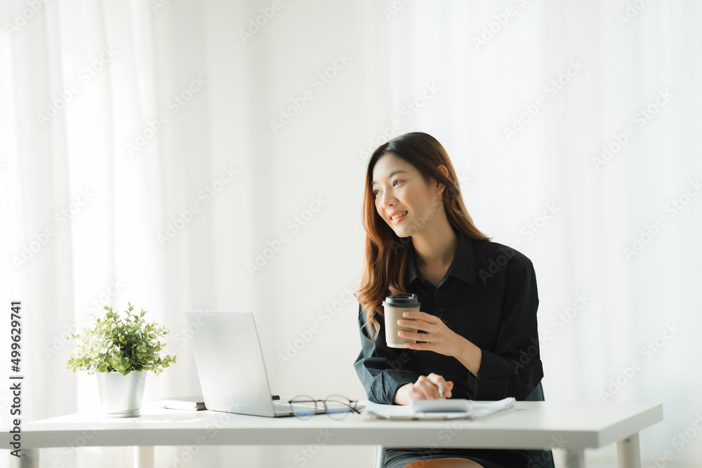 Beautiful young asian business woman drinking coffee and using laptop computer while working in office. Beautiful young asian business woman drinking coffee and using laptop computer while working in office.