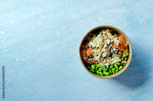 Top view of wok box, bowl of rice on background. Rice fried and stirred with salmon, avocado, onion, cucumber, broccoli, sesame. Chinese, Asian food delivery. Packaging for woks. 