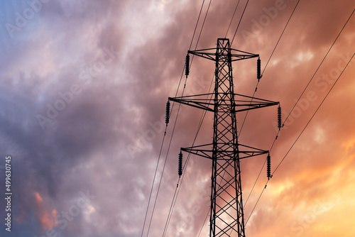 Detail of a British Style Electricity Pylon and suspended electic cables against a Blue Cloudy Sky