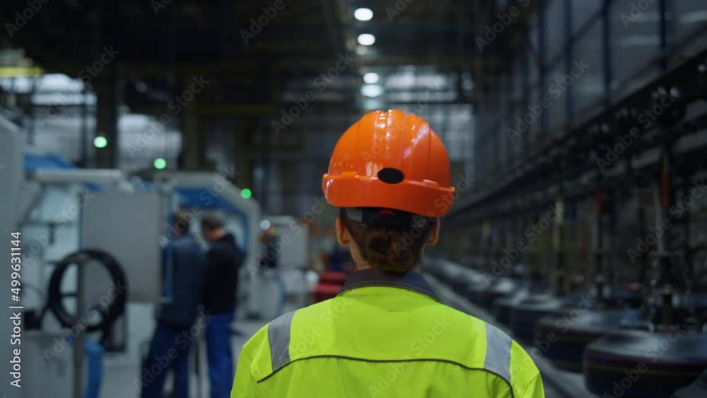 Back view mechanic walking plant. Huge industrial manufacturing modern warehouse Back view mechanic walking plant. Huge industrial manufacturing modern warehouse