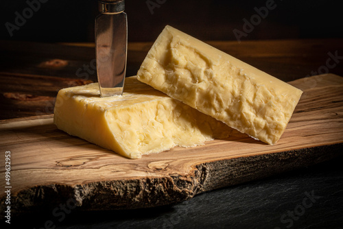 Close up of Quebec Cheddar Cheese on a Wood Board with a Cheese Knife