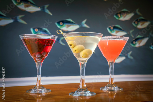 Three Cocktails in front of a Fish Background on a Wooden Table