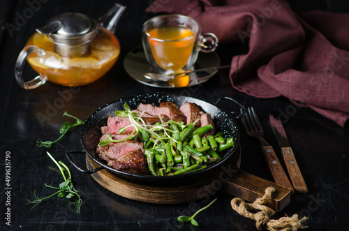 Ribeye steak with green beans in a pan. photo