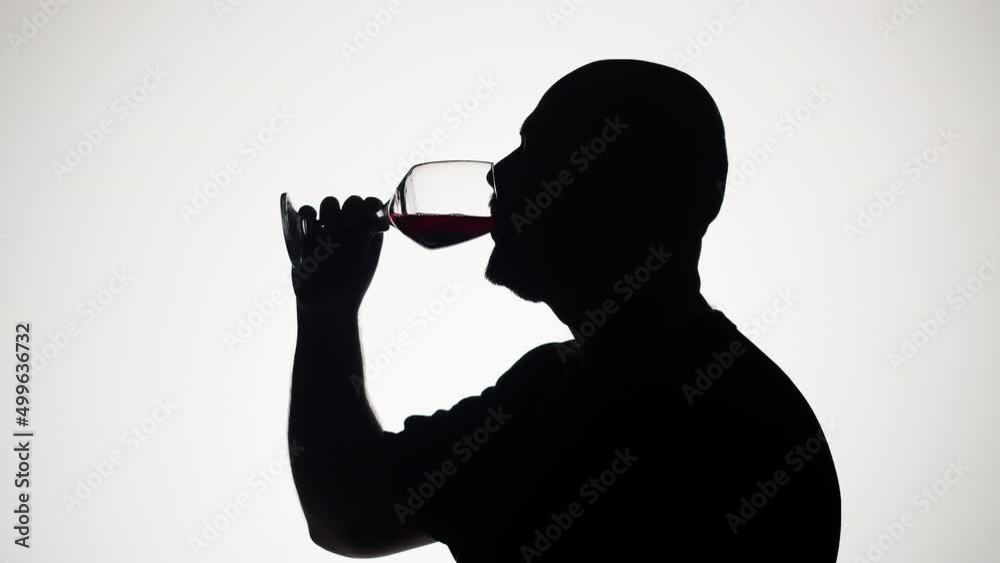 Man drinking wine on white background. Shadow silhouette of male person celebrating holiday in bar. Romantic evening. Man drinking wine on white background. Shadow silhouette of male person celebrating holiday in bar. Romantic evening.