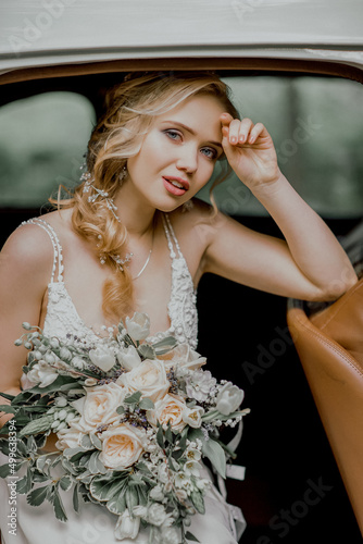 Beautiful bride with a bouquet in a vintage car.