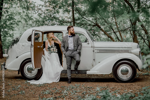 The bearded groom and beautiful bride. Retro car.