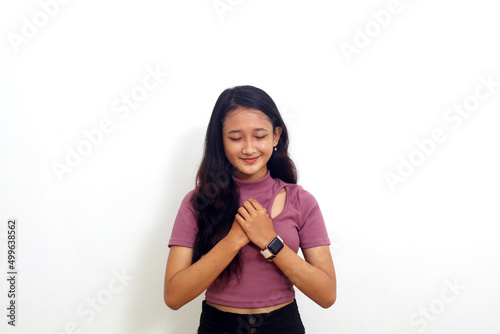 Asian young woman holding chest while feeling relieved. Isolated on white background