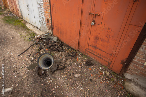 Close-up view stock image of real unexploded military missile, torpedo or shell stuck in ground near doors of garages outdoors. Moments of dreadful war of Russia against Ukraine in 2022 photo