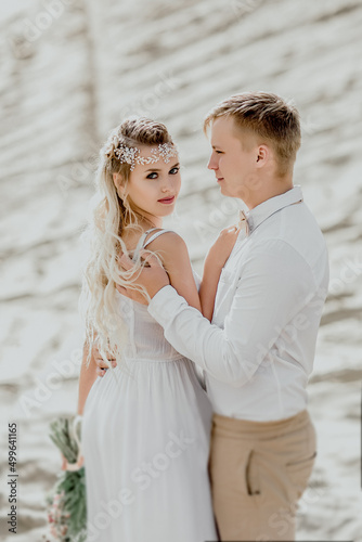 The bride and groom on the background of sand. Beautiful couple.