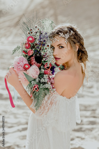 Beautiful blonde bride looking at the camera. On the beach.