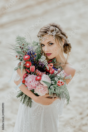 Beautiful bride on a sandy beach. Beautiful wedding bouquet.