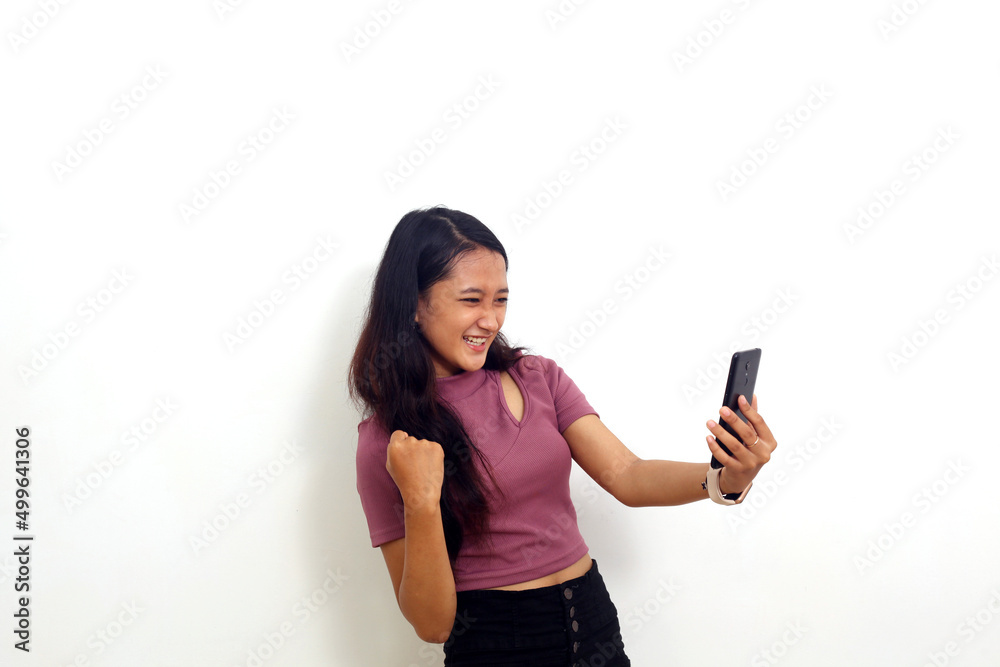 Happy asian young girl standing while get a good news from her cellular phone. Isolated on white