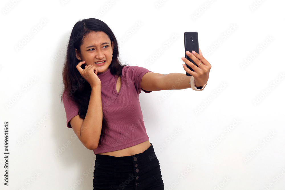 Scared young asian girl standing while getting a news from her mobile phone. Isolated on white