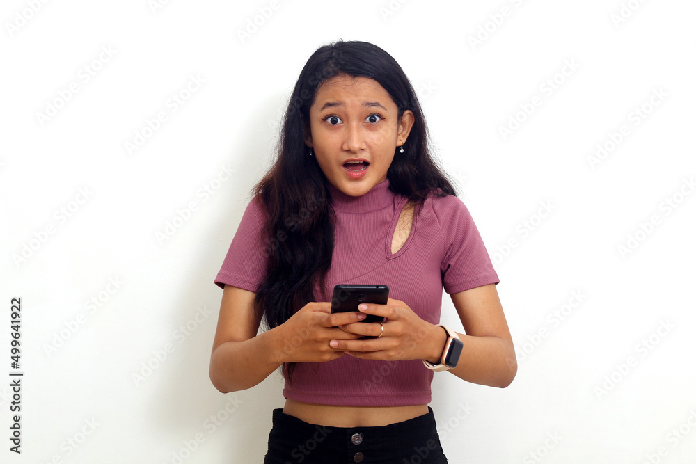 Asian girl holding cellphone with shocked expression. Isolated on white background Asian girl holding cellphone with shocked expression. Isolated on white background