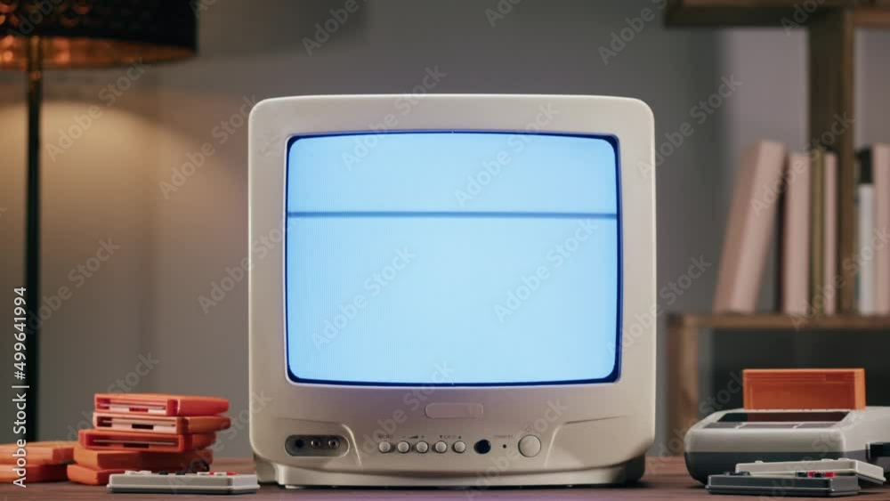 Old television with grey interference screen on home background. Close-up of vintage tv and cartridges for retro playstation. Antique video game, nostalgia. Old television with grey interference screen on home background. Close-up of vintage tv and cartridges for retro playstation. Antique video game, nostalgia.