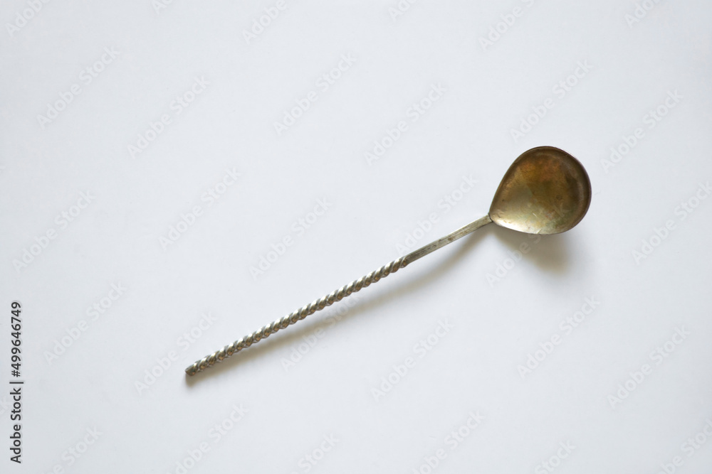 Old homemade teaspoon on a white table close up Old homemade teaspoon on a white table close up
