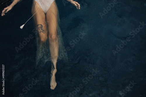 Overhead view of woman back floating in water with tattoo on thigh photo