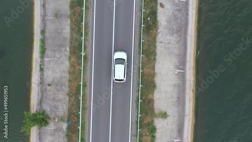 Wallpaper Mural Top view of white car rides through dam route. SUV drives at road near lake on summer day. Flying over the auto moves through bridge of river or pond. Scenic landscape way. Travel concept. Aerial shot Torontodigital.ca