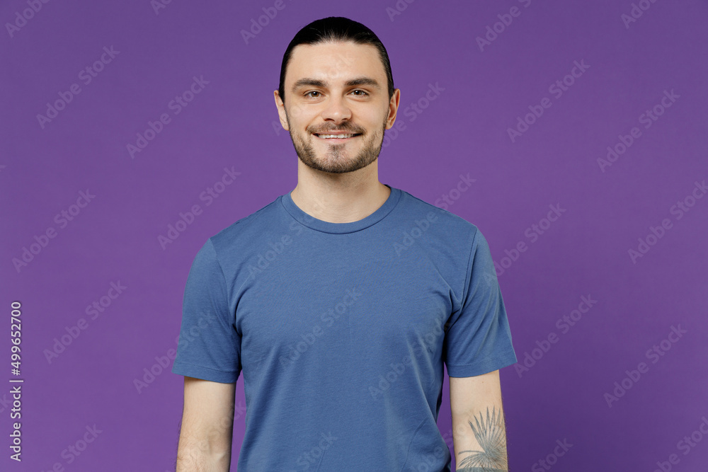 Young smiling attractive cheerful happy fun cool man 20s wearing blue t-shirt with blank print design look camera isolated on plain purple color background studio portrait. People lifestyle concept Young smiling attractive cheerful happy fun cool man 20s wearing blue t-shirt with blank print design look camera isolated on plain purple color background studio portrait. People lifestyle concept