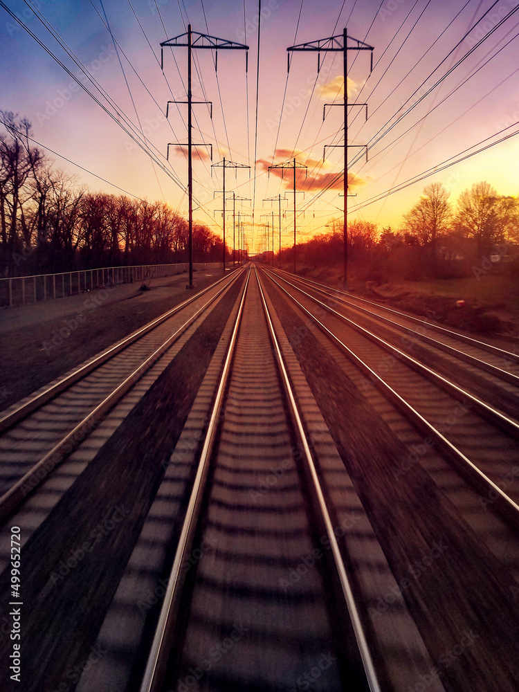 Traveling on railroad train tracks into setting sunlight on the distant horizon Traveling on railroad train tracks into setting sunlight on the distant horizon