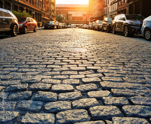 Cars parked along the sidewalk of a historic cobblestone street in the Tribeca neighborhood of Manhattan in New York City