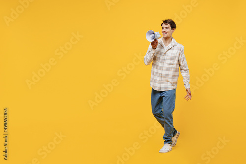 Full body young smiling happy fun cheerful caucasian man 20s wearing white casual shirt hold scream in megaphone announces discounts sale Hurry up isolated on plain yellow background studio portrait.