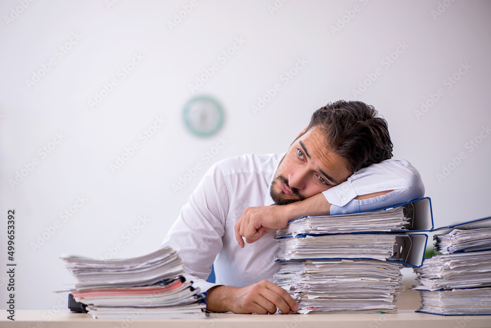 Young male employee and too much work in the office Young male employee and too much work in the office