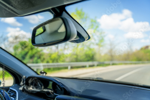 Summer travel concept and abstract background, view from the front window of the car to the road and the rearview mirror. Soft focus image © olezzo