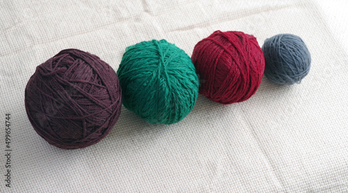 Balls of yarn for knitting in different colors against the background of coarse fabric. Selective focus..