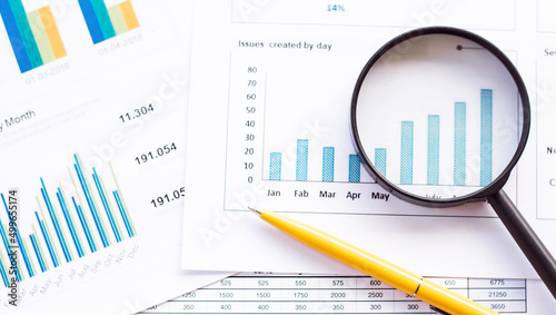 Business concept, magnifying glass pencils and pen on financial charts and graphs