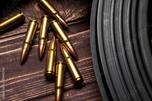 Bullets and Kalashnikov assault rifle on wooden background. Cartridges 7.62 caliber for ak 47 closeup. Selective focus photo