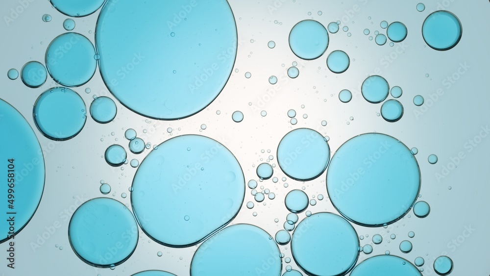 Blue oil drops floating in transparent fluid against pale blue background | Background for body care gel commercial shot Blue oil drops floating in transparent fluid against pale blue background | Background for body care gel commercial shot