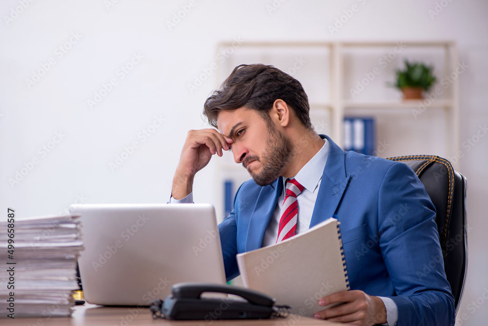 Young male employee and too much work in the office Young male employee and too much work in the office