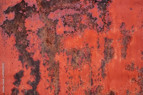 Old red painted metal surface with extensive corrosion spots background.