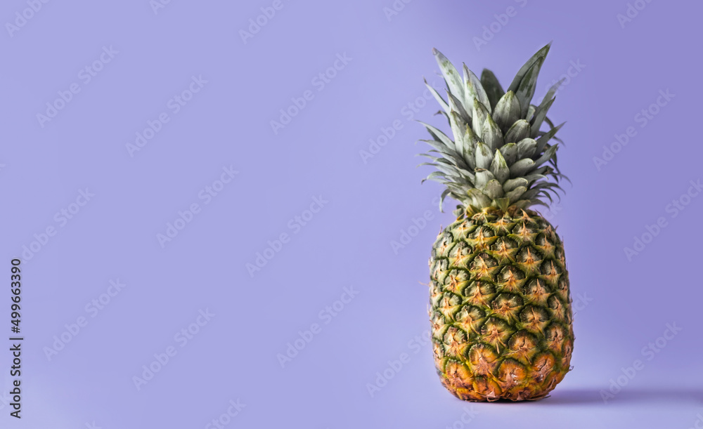 Whole pineapple on the purple background with copy space for your text. Color of year 2022 Very Peri background with tropic feel