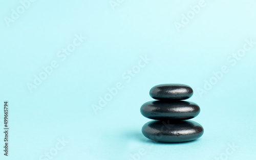 A stack of black zen balance stones on a blue background. The concept of a SPA center. A stage for promotion  sale  presentation or cosmetics. Copy space