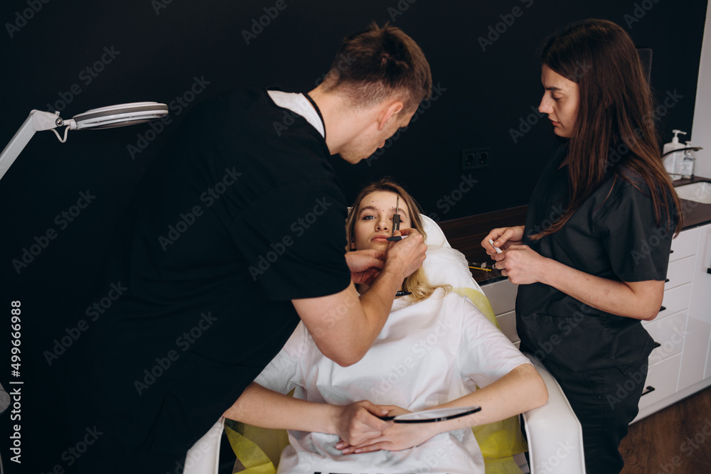 Obraz premium Plastic surgeon drawing marks on female face in clinic