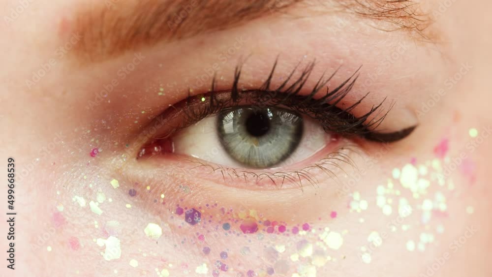 Blue eye close-up, glitter on low eyelid, painted lashes. Optical shop concept. Advertising of contact protective lenses for vision improvement. The shooting of human face. Blue eye close-up, glitter on low eyelid, painted lashes. Optical shop concept. Advertising of contact protective lenses for vision improvement. The shooting of human face.