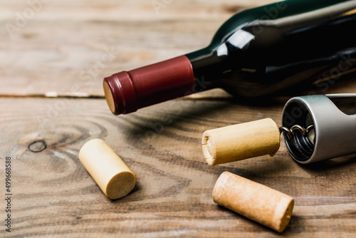 bottle with red wine and corkscrew on wooden background