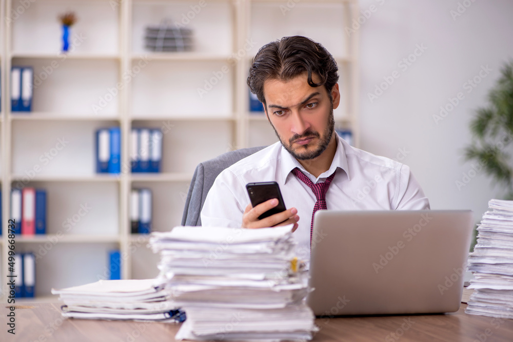 Young male employee and too much work in the office Young male employee and too much work in the office
