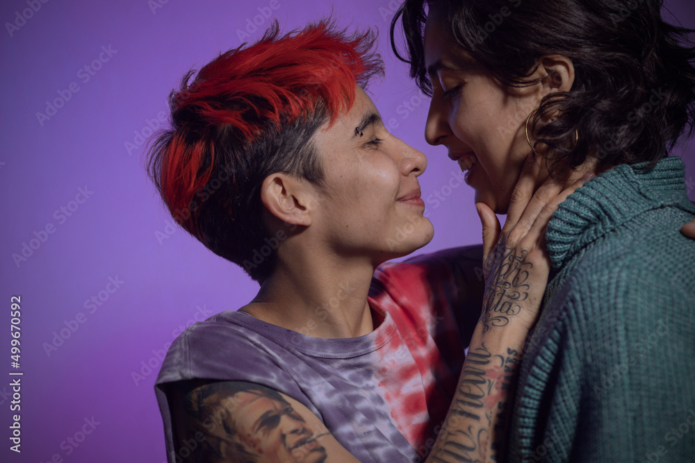 Naklejka premium close up of a lesbian couple about to kiss against a blue background