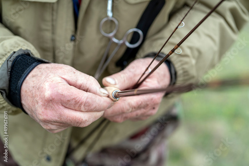 Preparing for fly fishing. Close-up of a fisherman s hand adjusting fly fishing rods for fishing on the river.