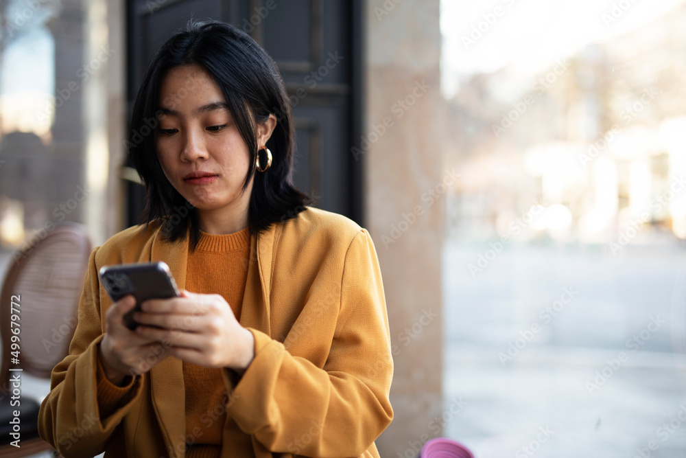 Happy Chinese girl checking phone. Beautiful young girl typing a message.. Happy Chinese girl checking phone. Beautiful young girl typing a message..
