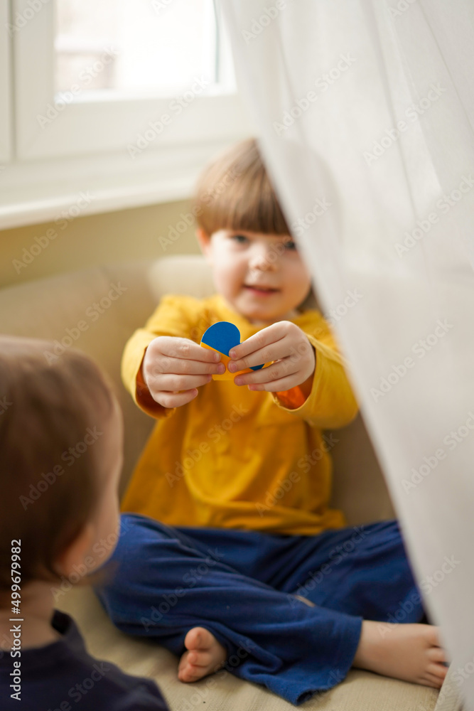 War in ukraine the baby looks out the window with the flag of ukraine War in ukraine the baby looks out the window with the flag of ukraine