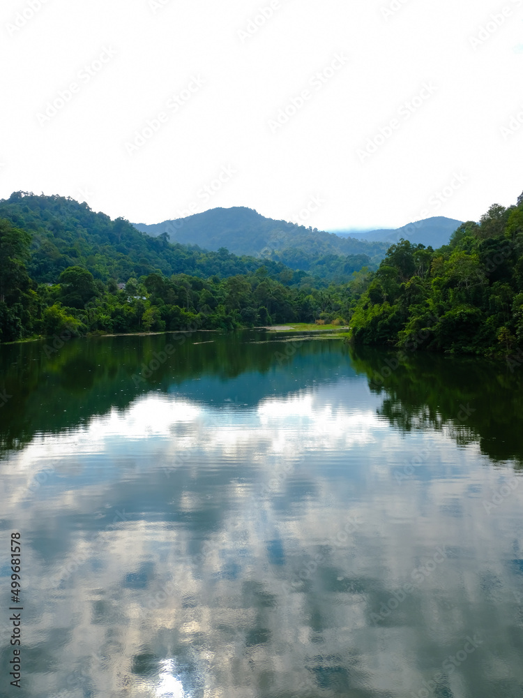 Calm view of dam water surrounded with green trees in Kuala Kubu Bharu, Selangor, Malaysia.