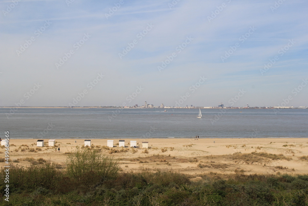 a dutch coast landscape in breskens with a sand beach with beach houses and dunes and flushing at the other side of the westerschelde sea